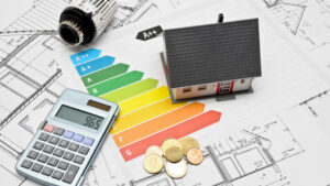 Symbolbild mit Taschenrechner, Münzen, Miniaturhaus und Abbildung der Energieeffizienzklassen zur Fördermittelbeantragung mit dem Energie-Effizienz-Experten
