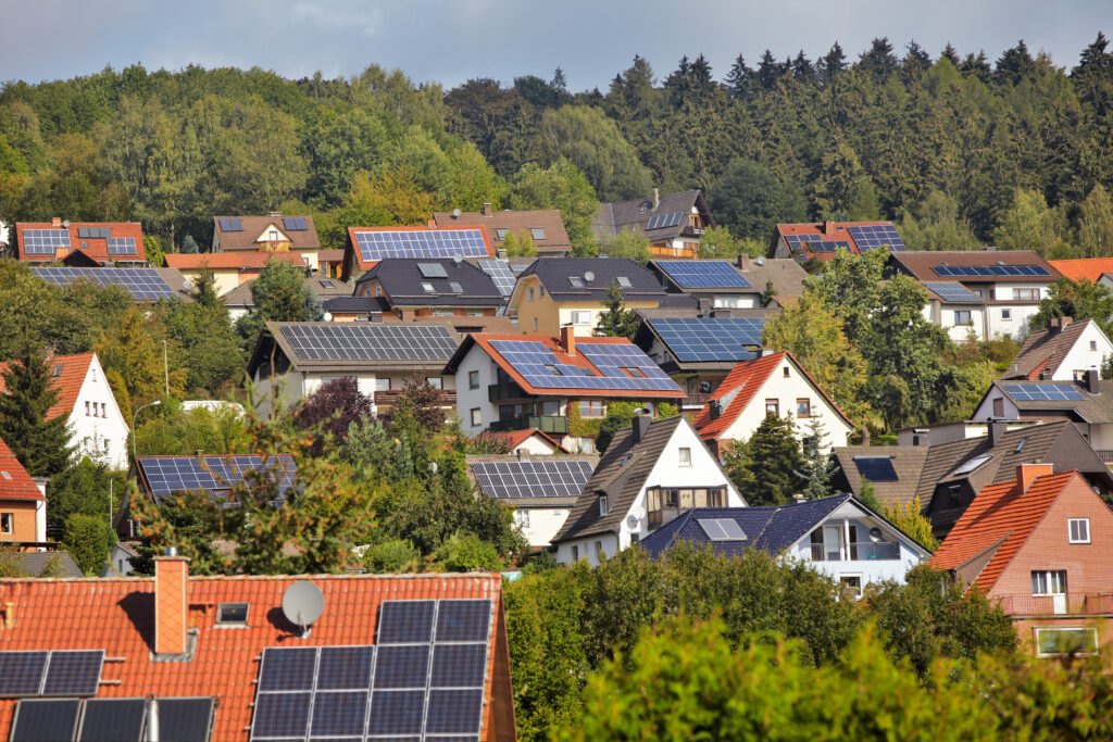 Mehrere Wohnhäuser aus der Ferne, die fast alle mit Solarpanelen zur Energieversorgung bestückt sind.